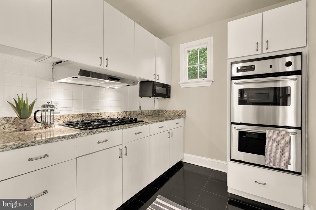 Kitchen with white cabinetry, granite counters, a gas cooktop, and stainless steel double wall ovens.