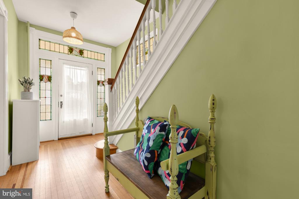 Entryway with stained-glass sidelights, a white staircase, and a green wooden bench.