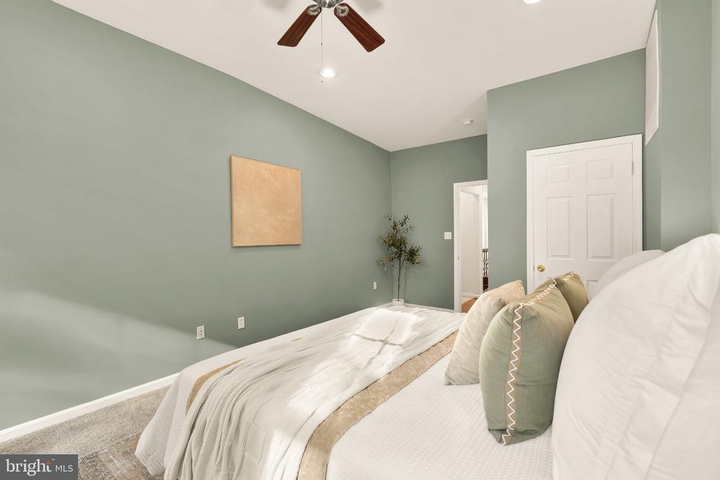 Bedroom with sage green walls, a white bed, neutral bedding, and a ceiling fan.