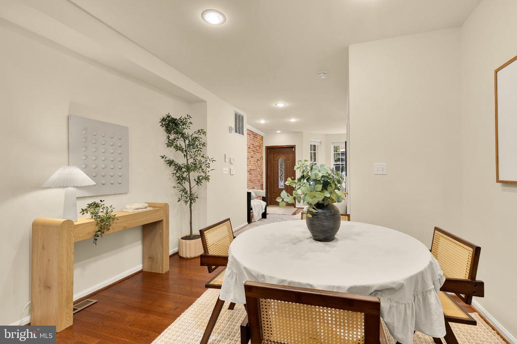 Dining room with a round white-clothed table, cane-back chairs, and hardwood floors.