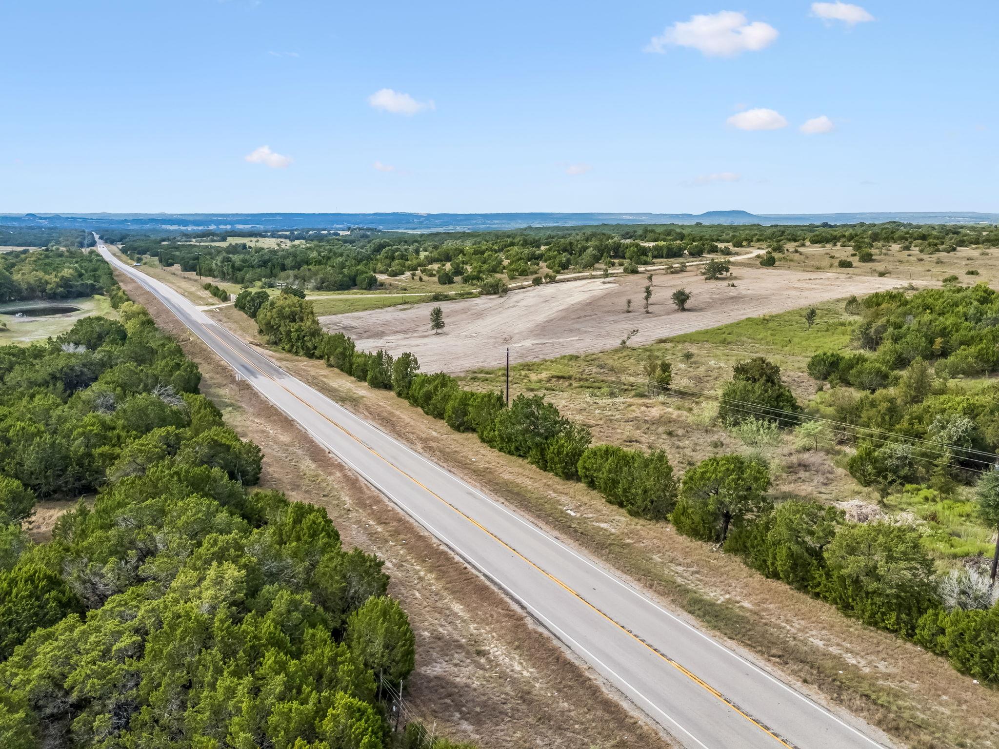 Aerial view of a cleared rural parcel beside FM 2484, surrounded by trees and scrub.