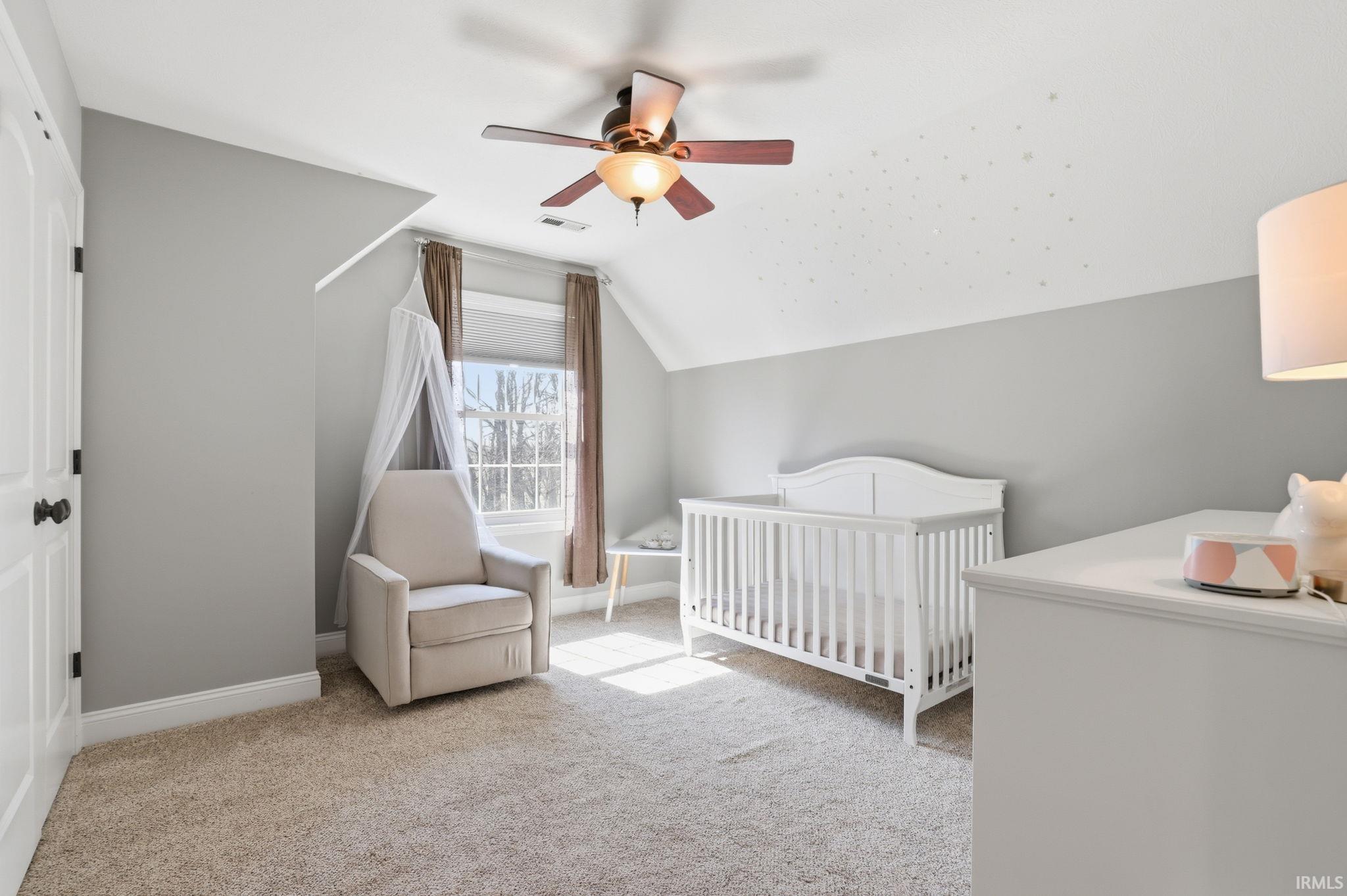 Nursery with a white crib, upholstered glider, and star-patterned sloped ceiling.