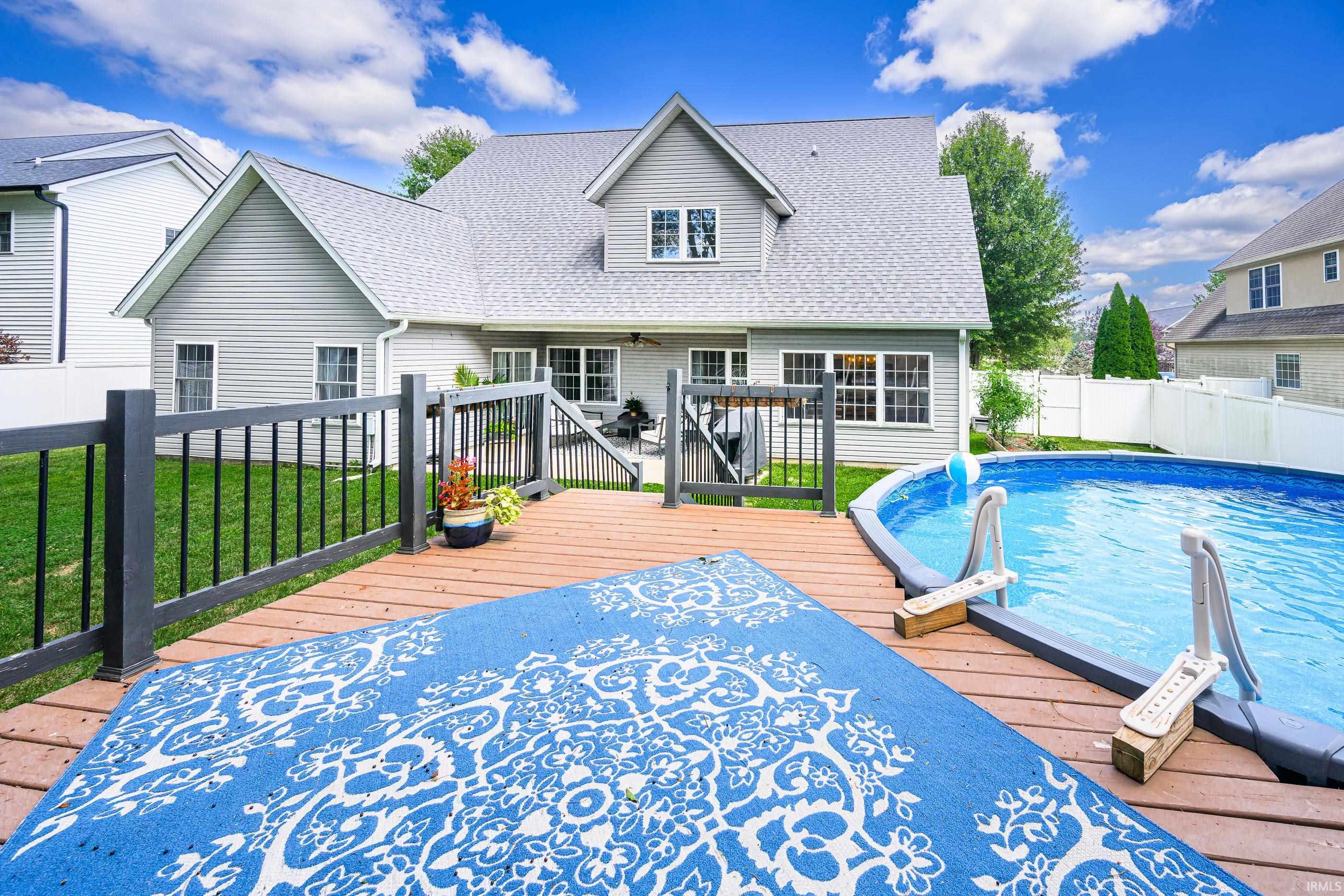House with a raised deck and above-ground pool in a fenced backyard.