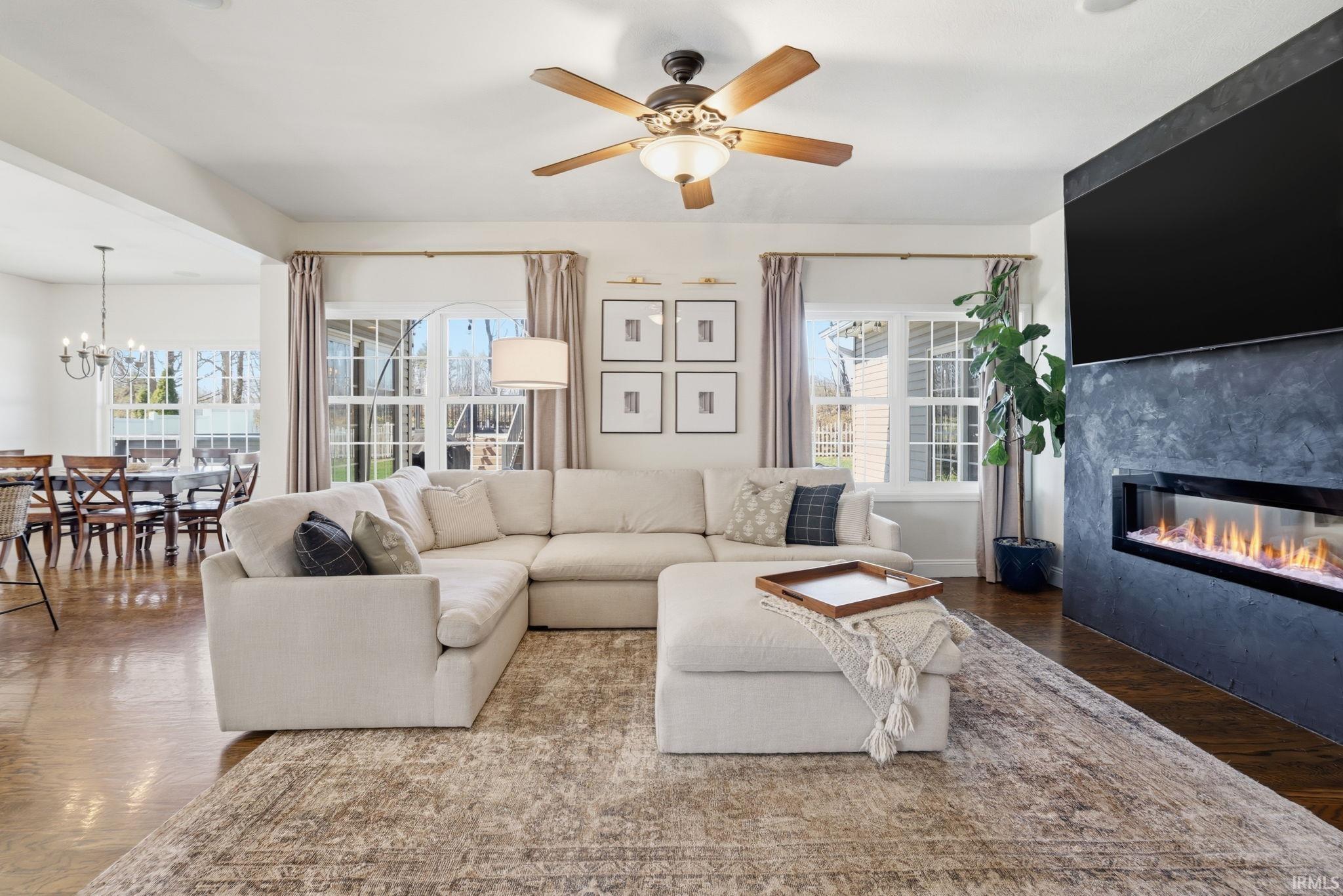 Furnished living room with a cream sectional, dark stone fireplace, and adjoining dining area.