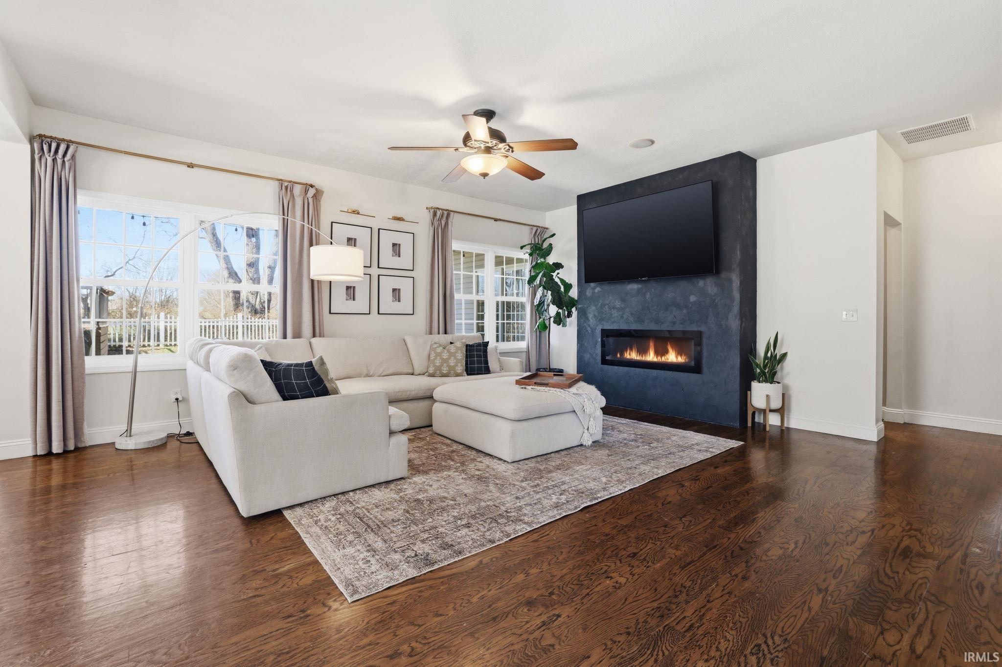 Living room with a light sectional, large windows, and a fireplace beneath a wall-mounted television.