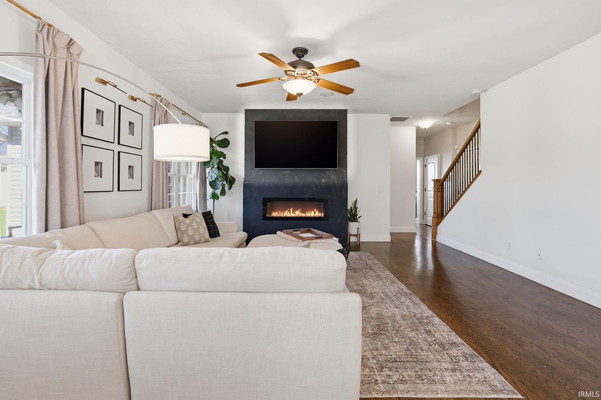 Furnished living room with a cream sectional facing a dark fireplace and mounted TV.