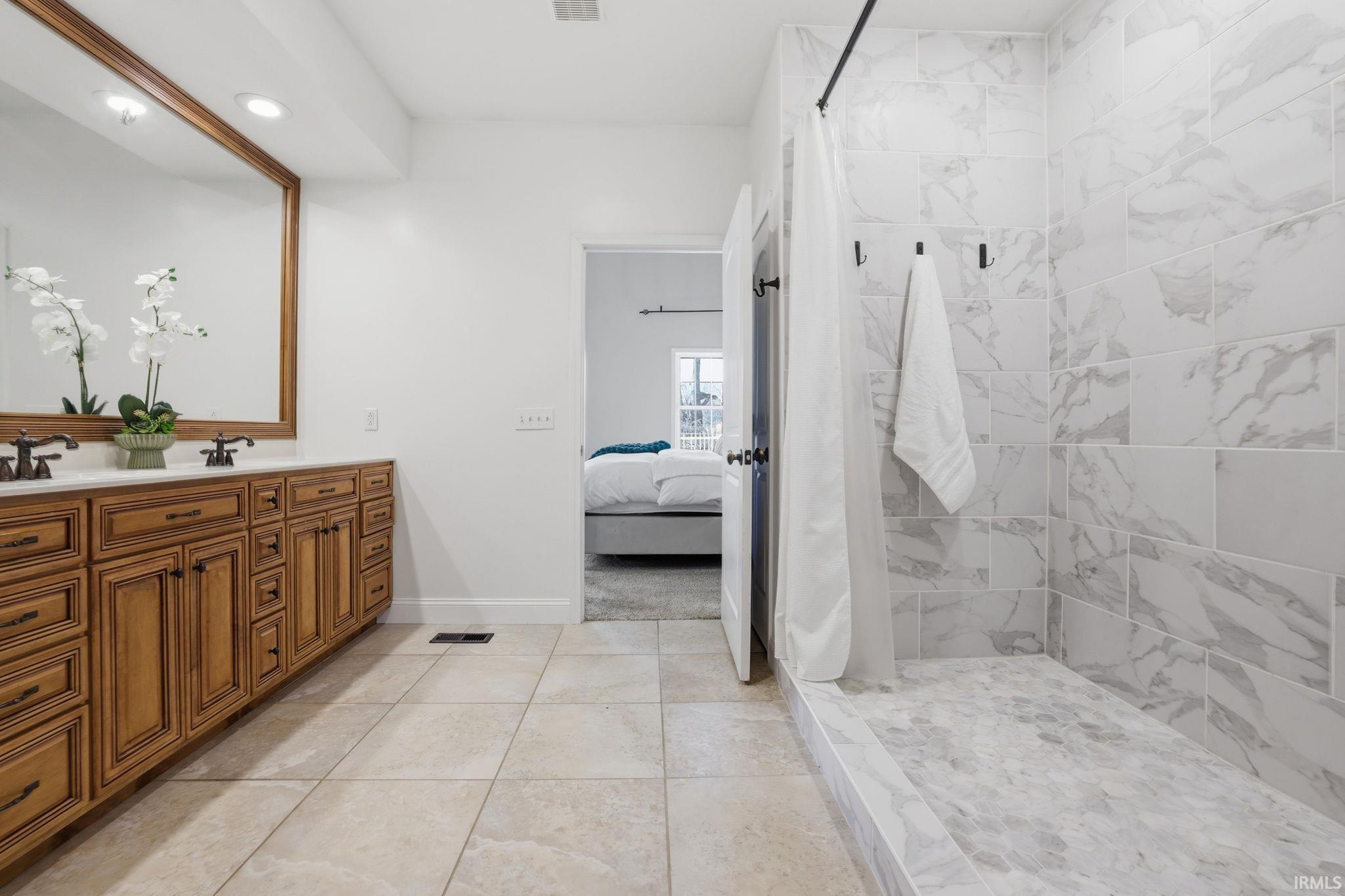 Bathroom with a carved wood vanity and a marble-look tiled walk-in shower.