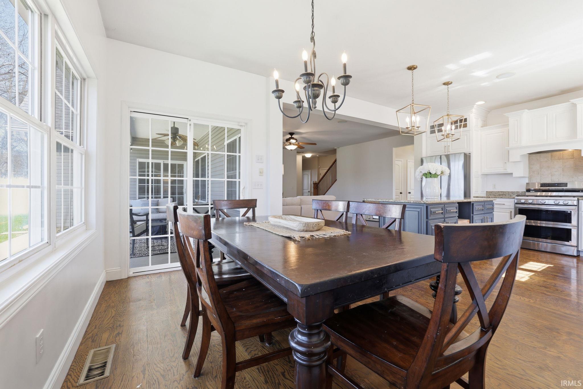 Dining room with a large dark wood table, tall windows, and an open kitchen with a blue island.