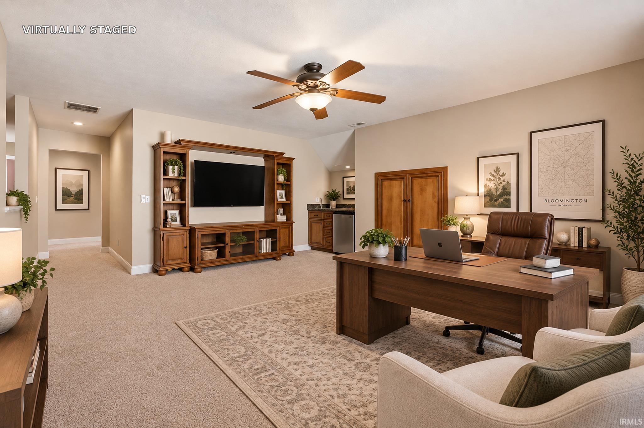 Virtually staged living room and office with a wooden media center, desk, leather chair, and Bloomington map.
