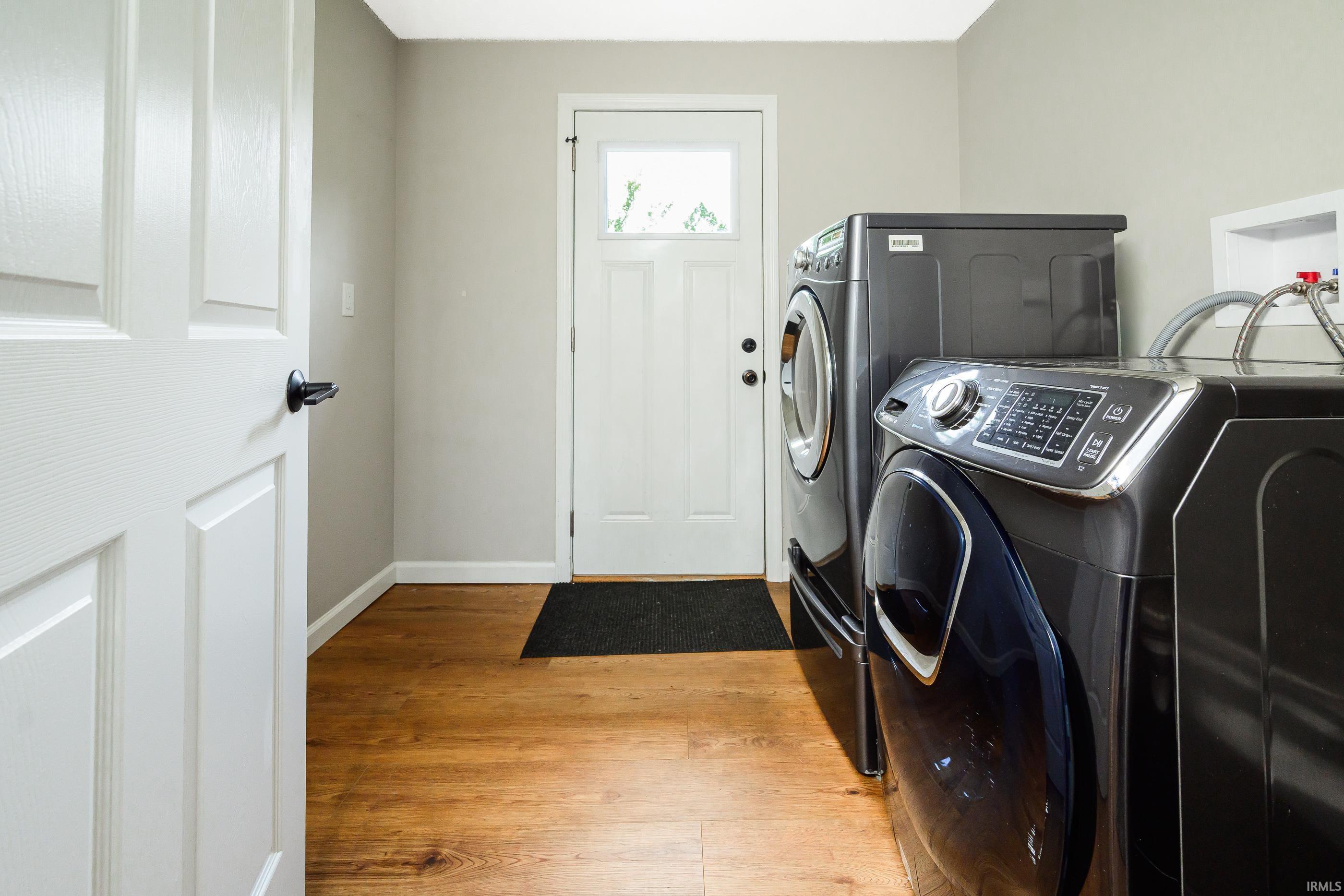 Laundry room with dark front-loading washer and dryer beside a white door.