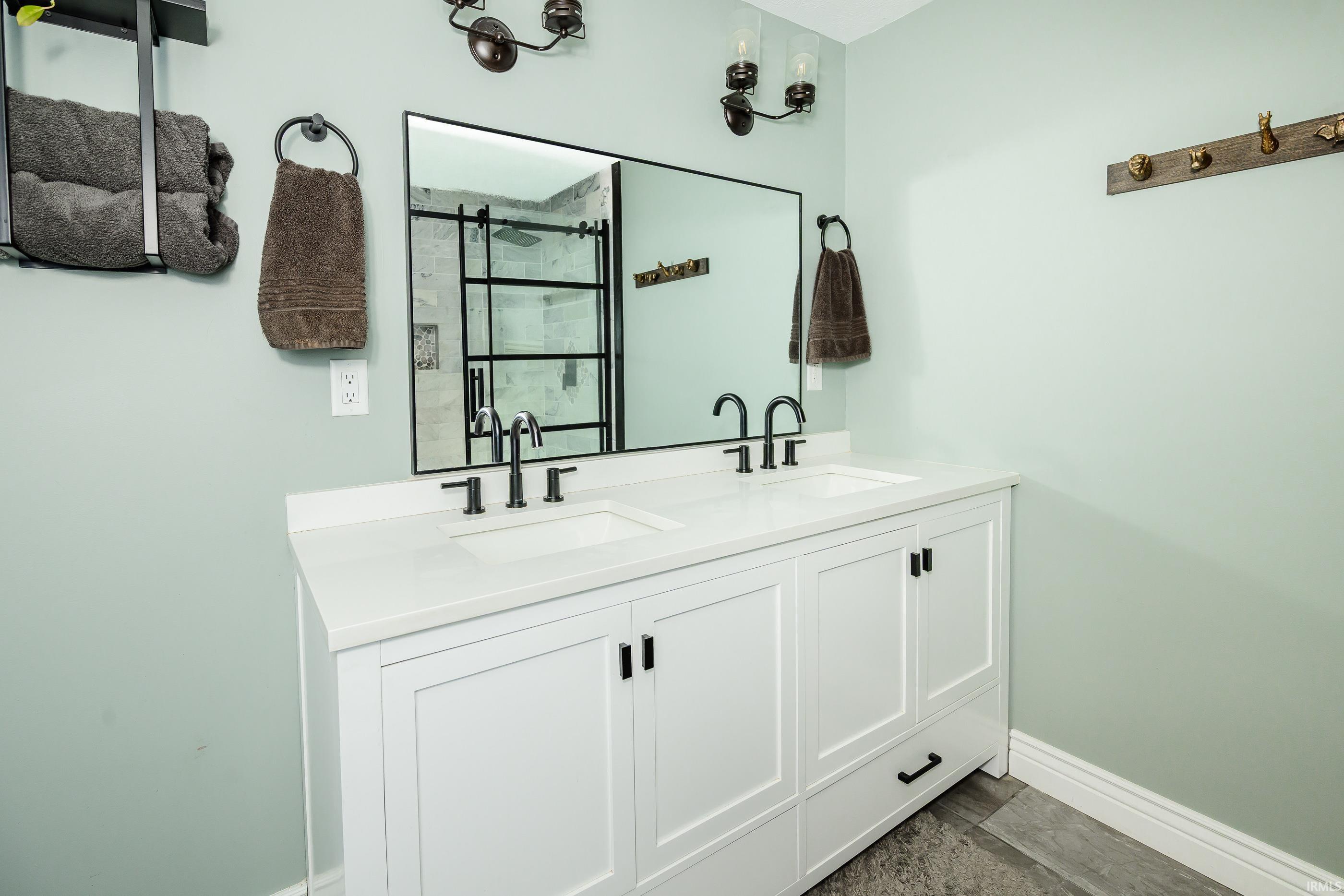 Bathroom with a white double-sink vanity, black fixtures, and a mirror reflecting a tiled shower.