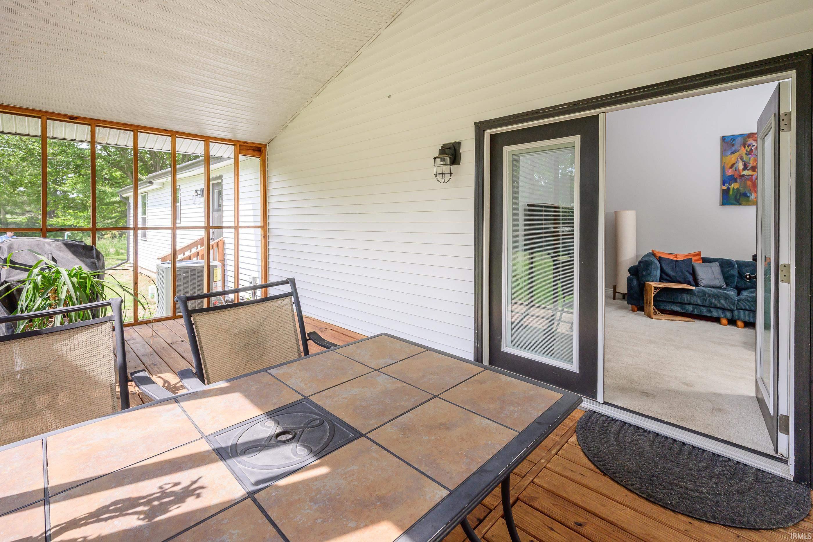 Screened porch with tiled table and chairs, opening to a living room with a blue sofa.