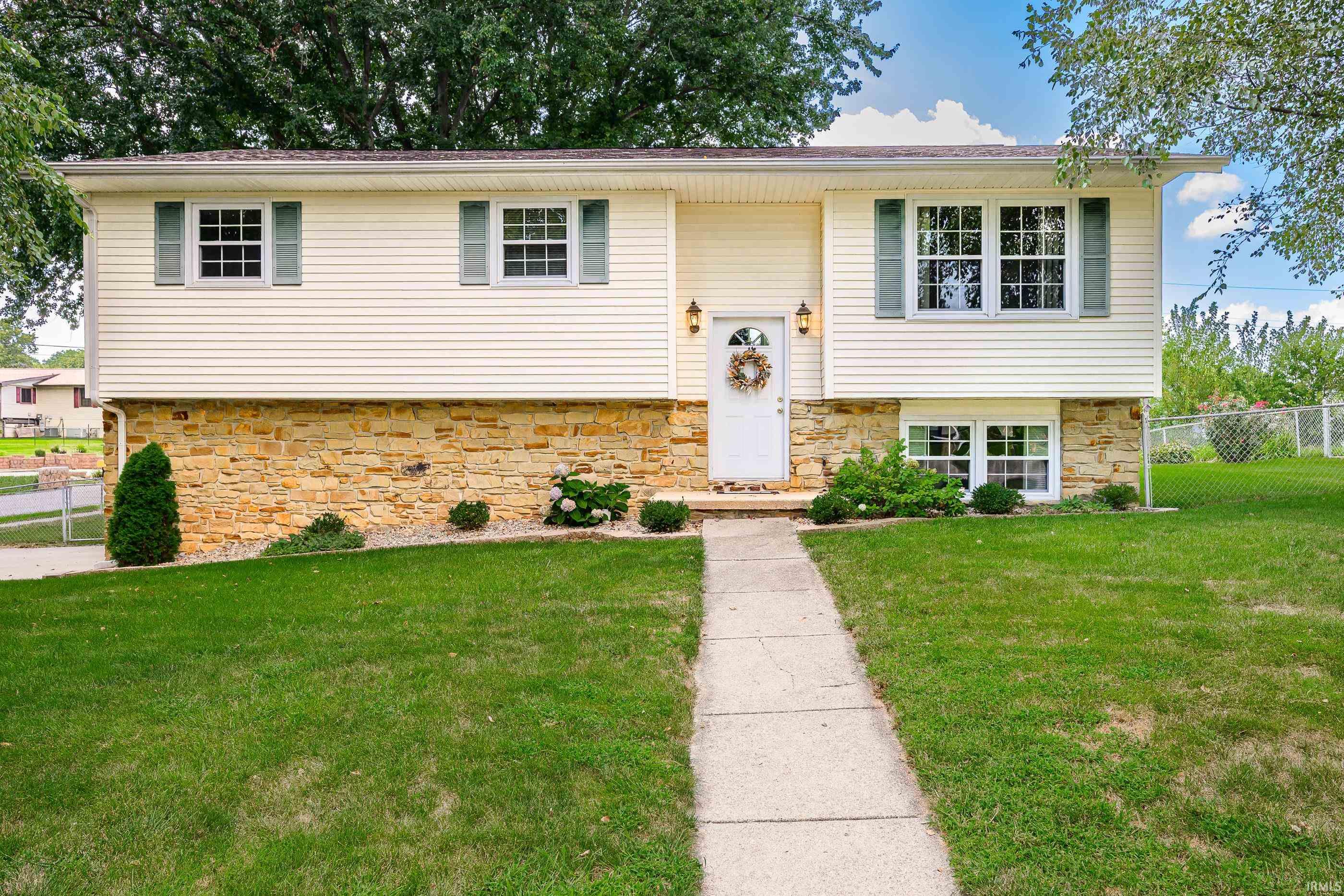 Split-level home with a stone lower facade, green shutters, and a walkway leading to the front door.