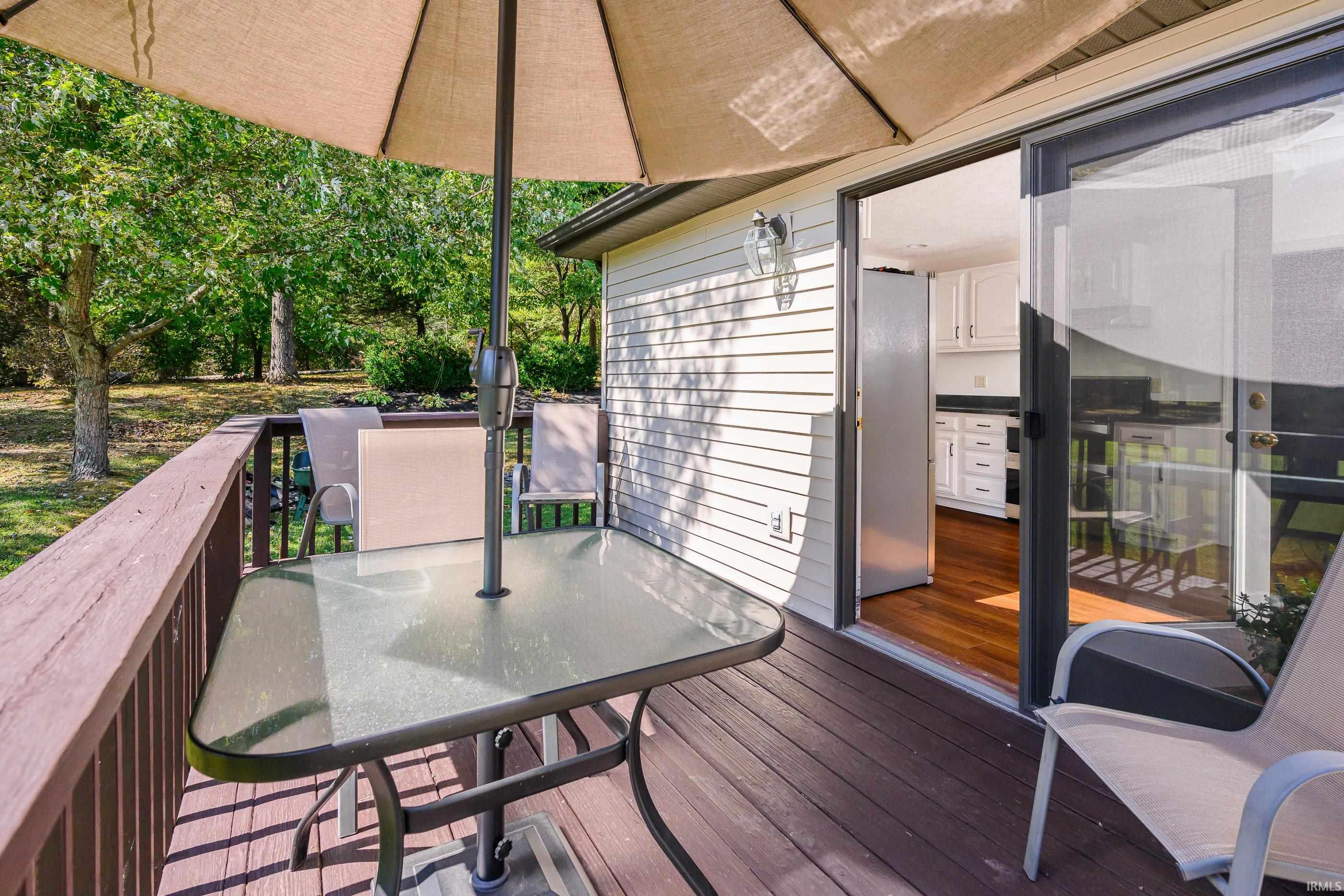 Wooden deck with patio furniture and umbrella beside an open sliding door to the kitchen.