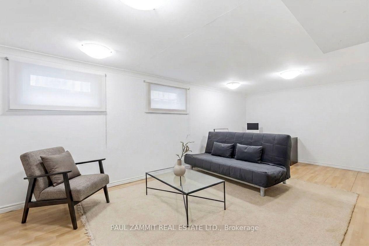 Living room with a dark gray sofa, upholstered armchair, and glass coffee table.