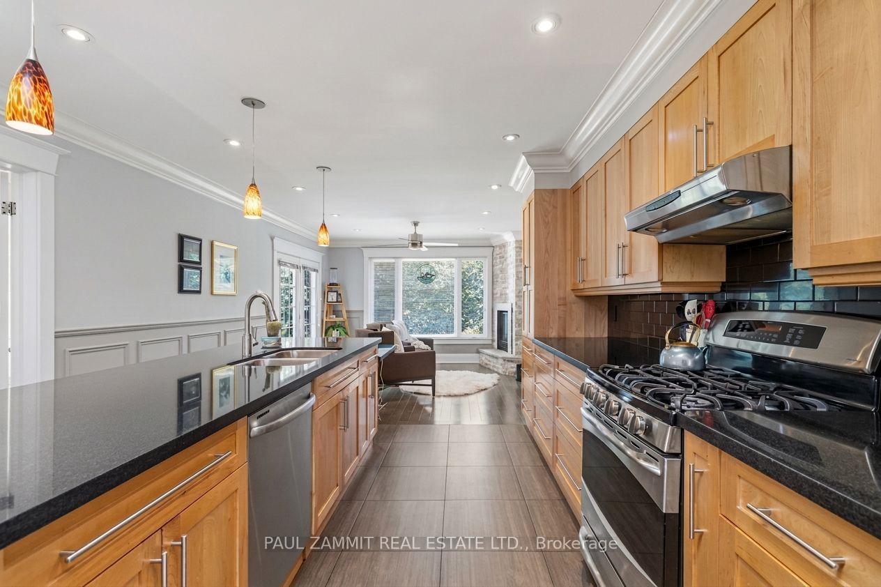 Kitchen with honey-colored wood cabinets, black counters, stainless steel appliances, and an island.