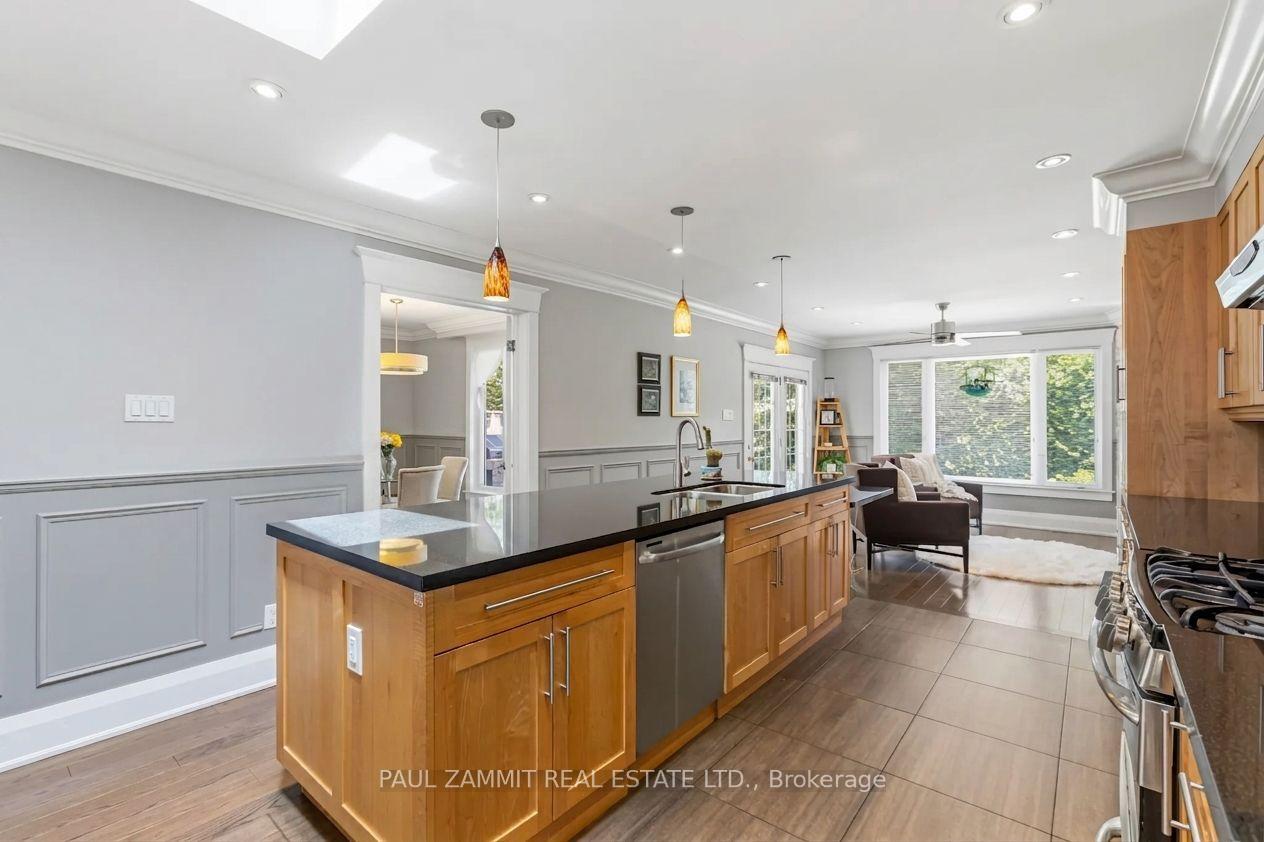 Kitchen with a large wood island and black countertops, opening into a living area with broad windows.