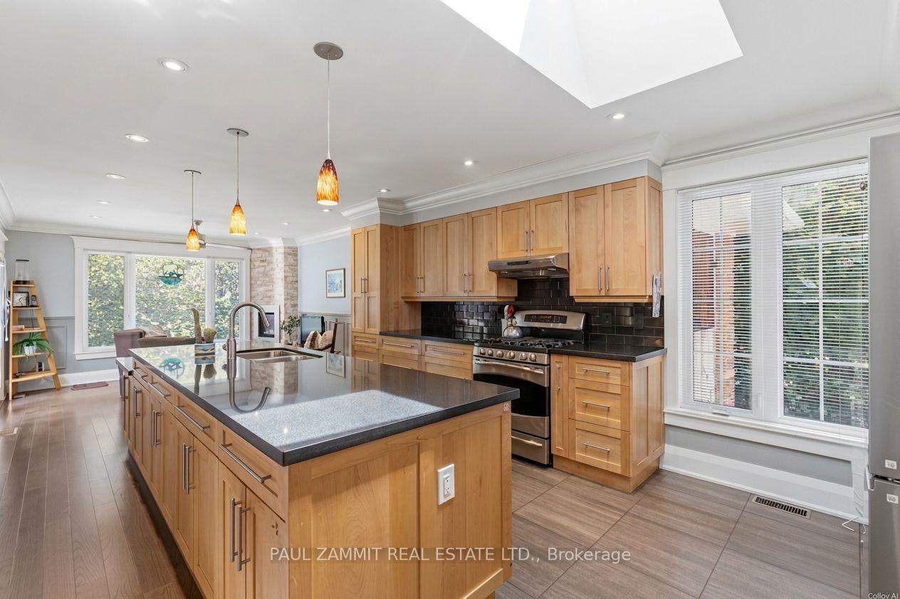 Open-plan kitchen with a large island, natural wood cabinets, and black tile backsplash.