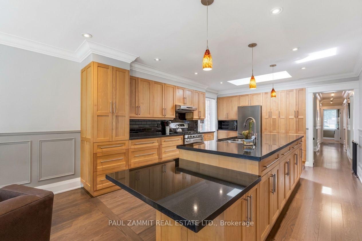 Kitchen with honey-toned cabinetry, black countertops, a large island, and a skylight.