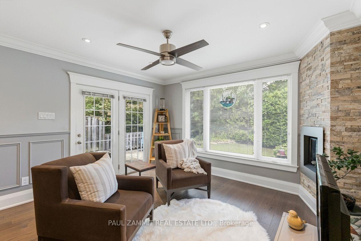 Living room with brown armchairs, a stone fireplace, and large windows overlooking greenery.
