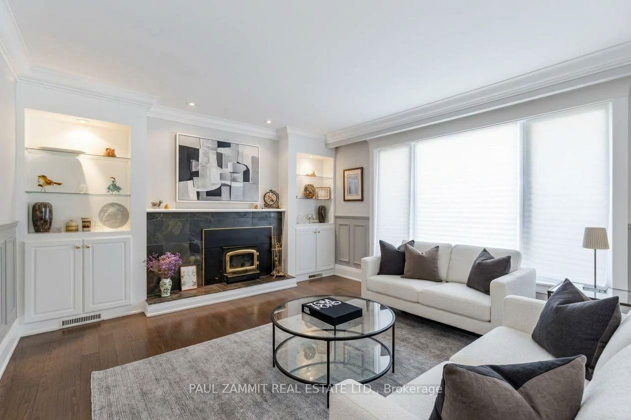 Living room with a dark tiled fireplace, built-in shelves, white sofas, and large windows.
