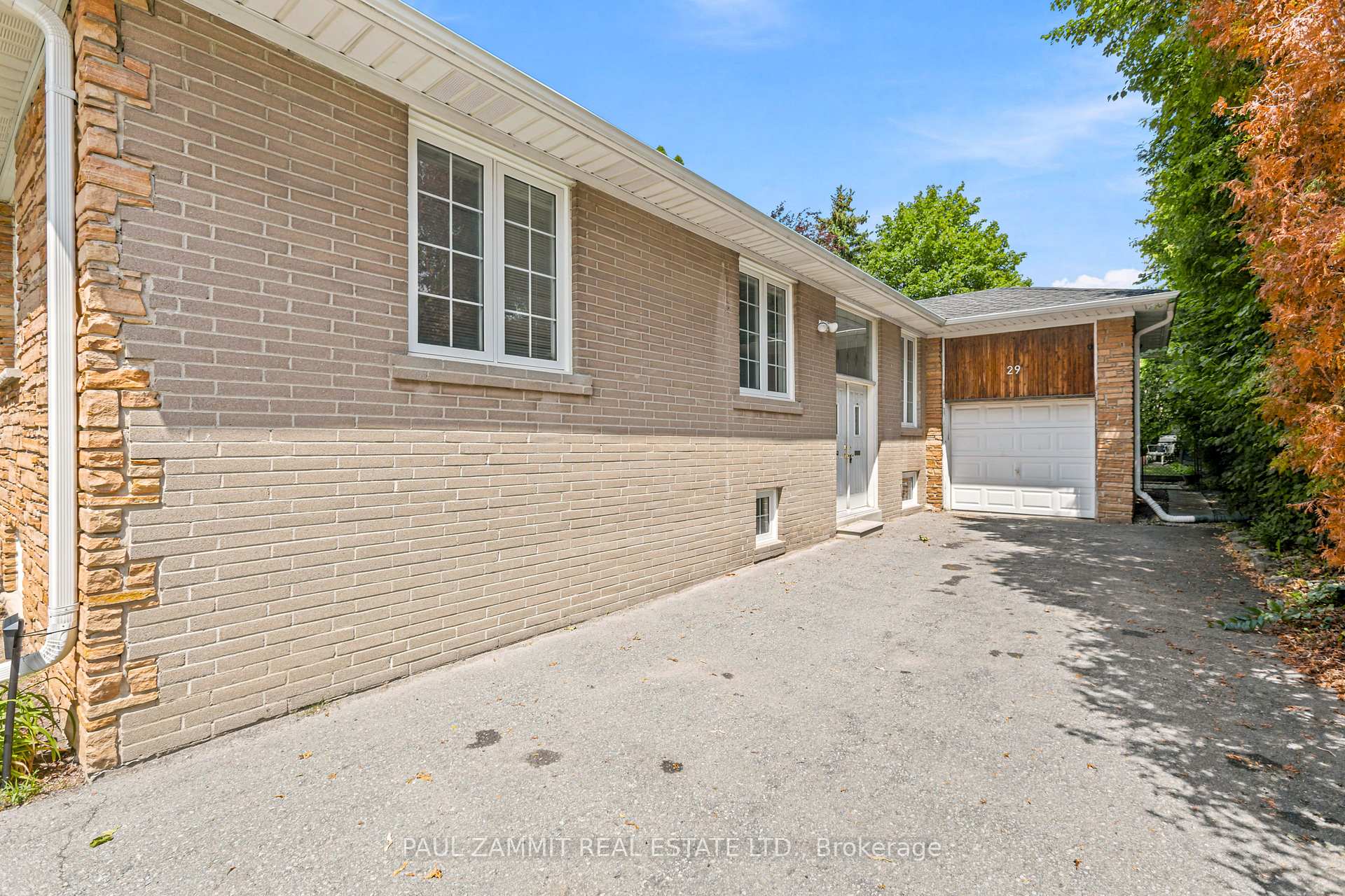 Brick house with stone accents, a white garage door, and a wide paved driveway.