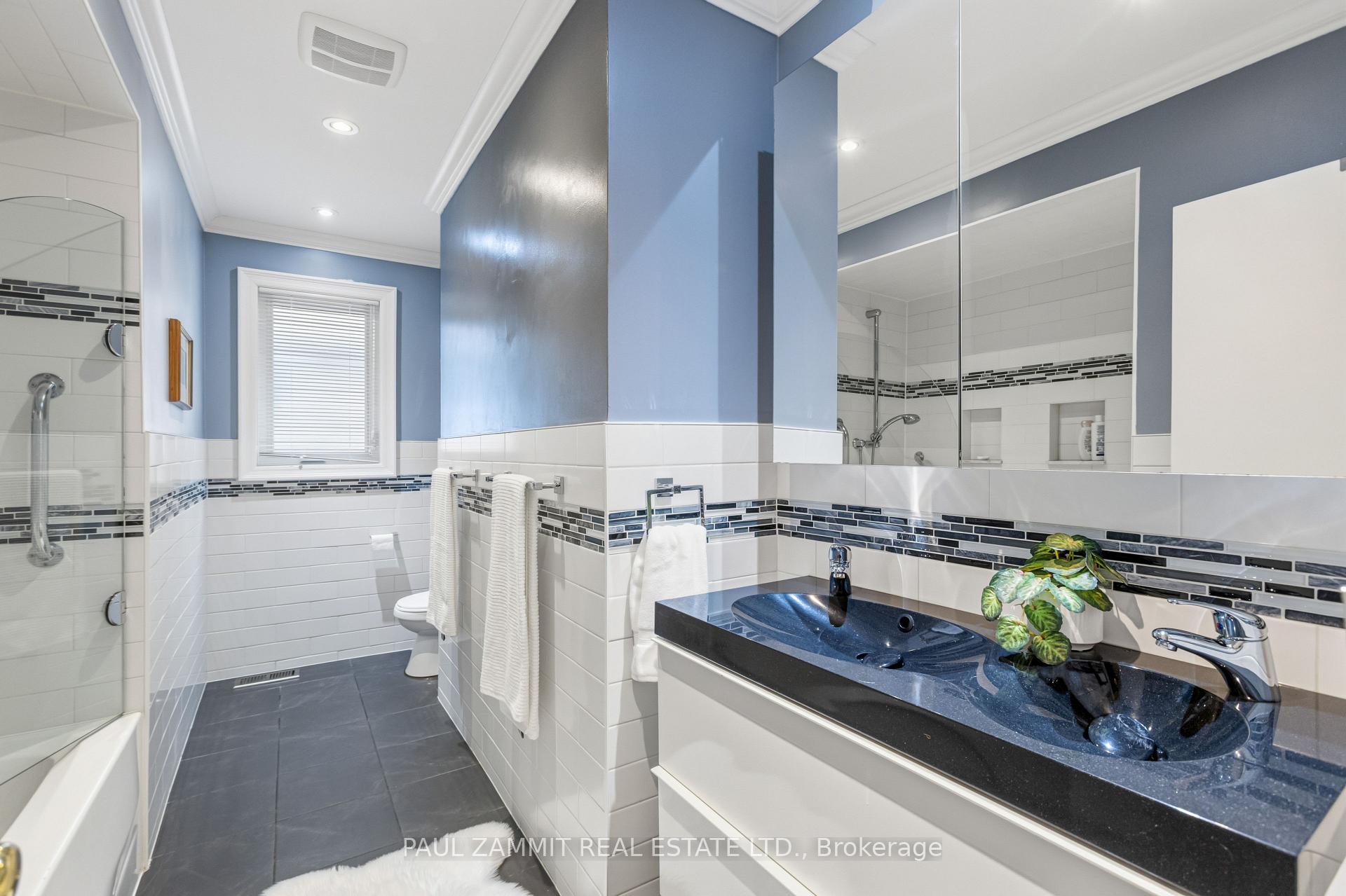 Bathroom with blue walls, white tile, glass shower, and double blue vessel sinks.