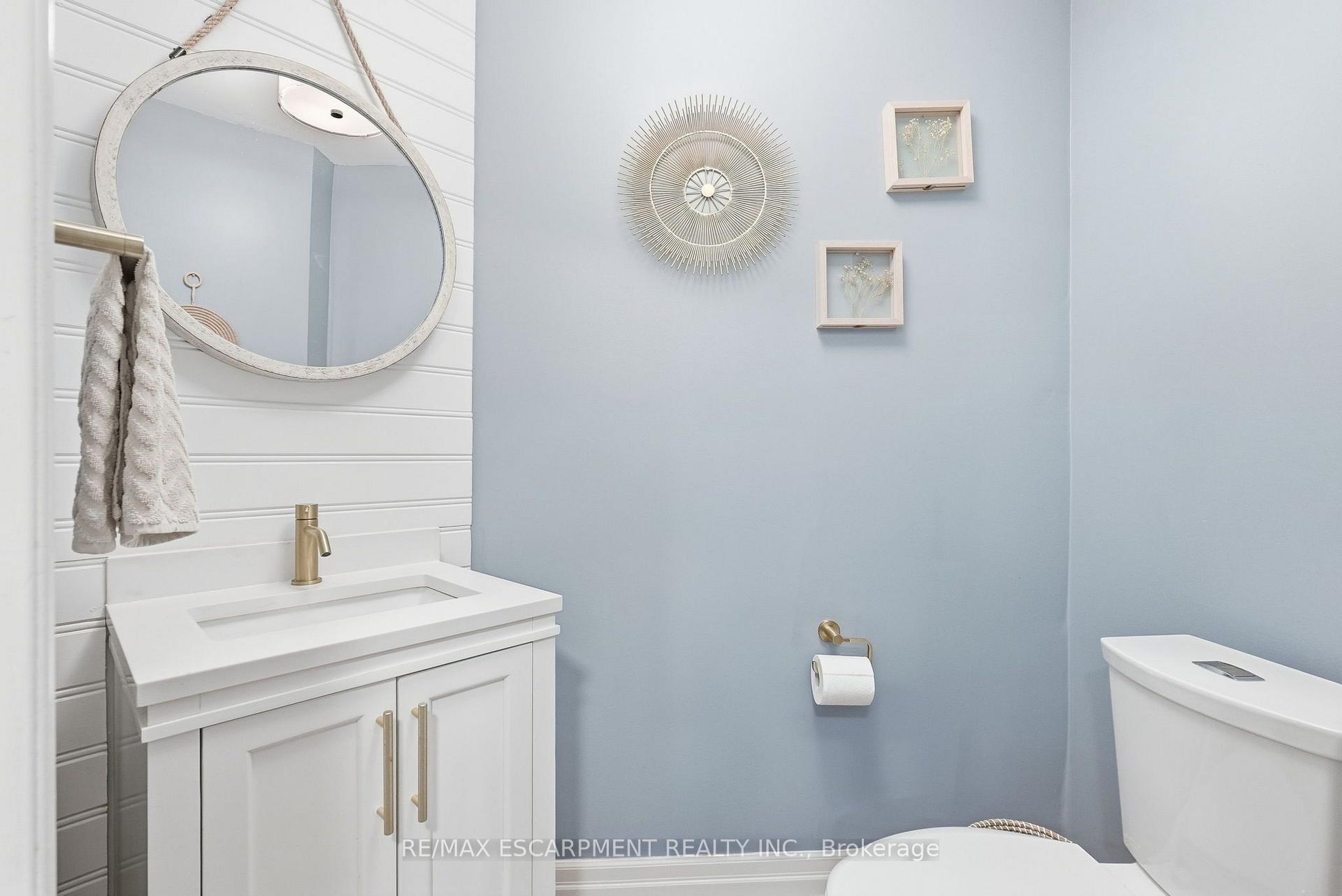 Bathroom with white vanity, oval mirror, pale blue walls, and brass fixtures.
