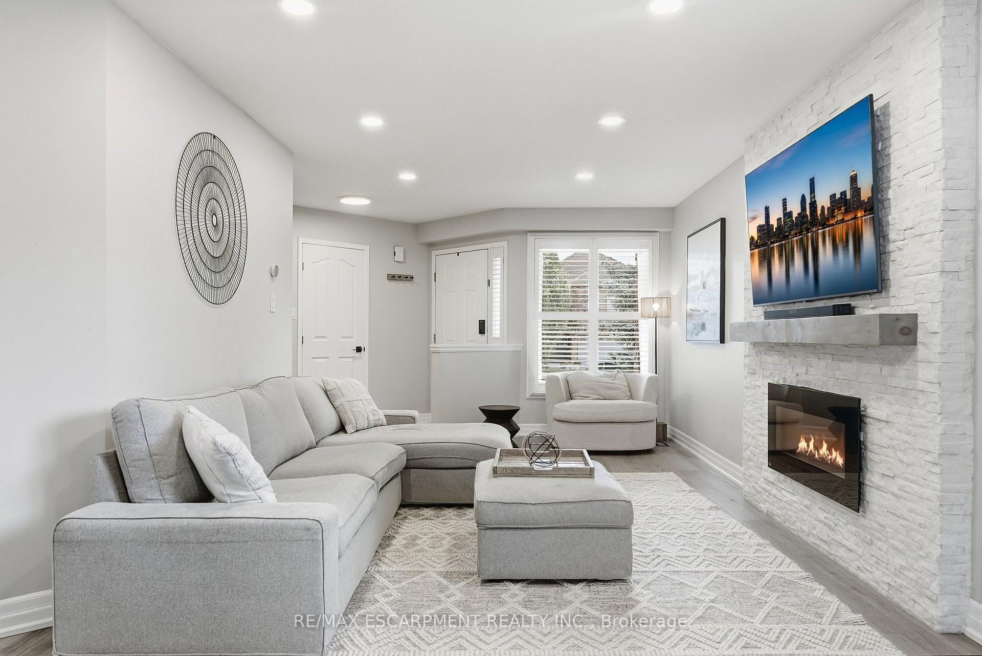 Living room with a gray sectional and a white brick fireplace with a lit fire.