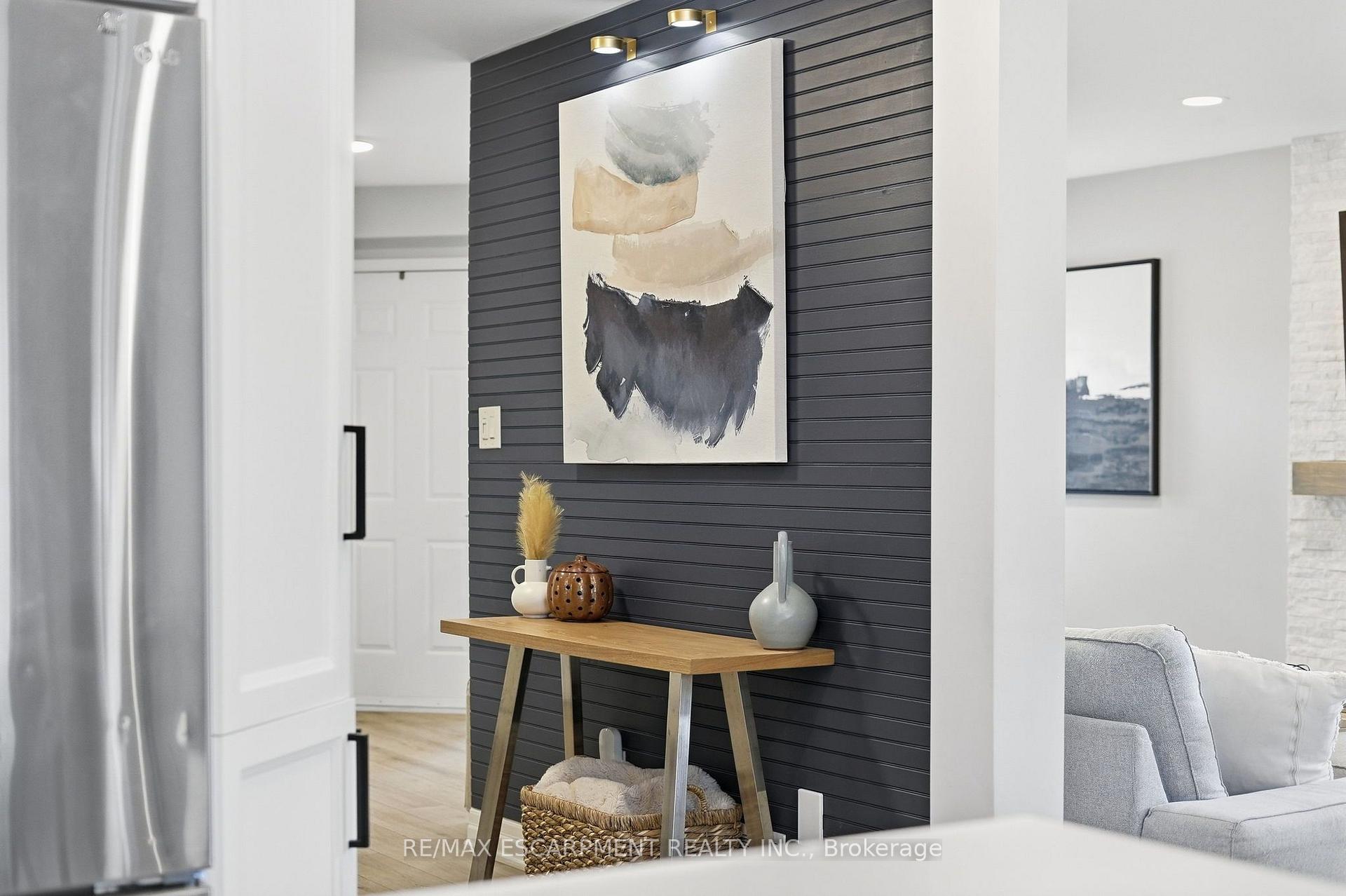 Entryway with a charcoal slat wall, abstract art, and a wooden console table with decorative vases.