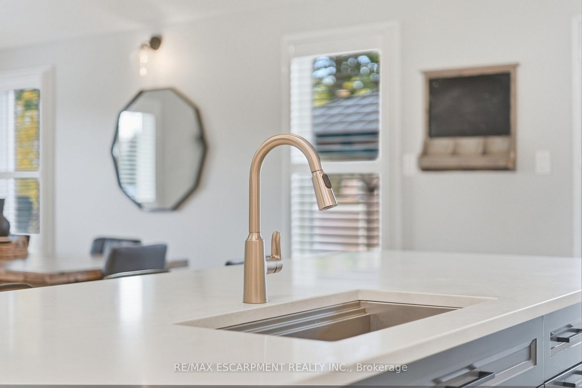 Modern kitchen island with a brushed brass pull-down faucet and inset stainless steel sink.
