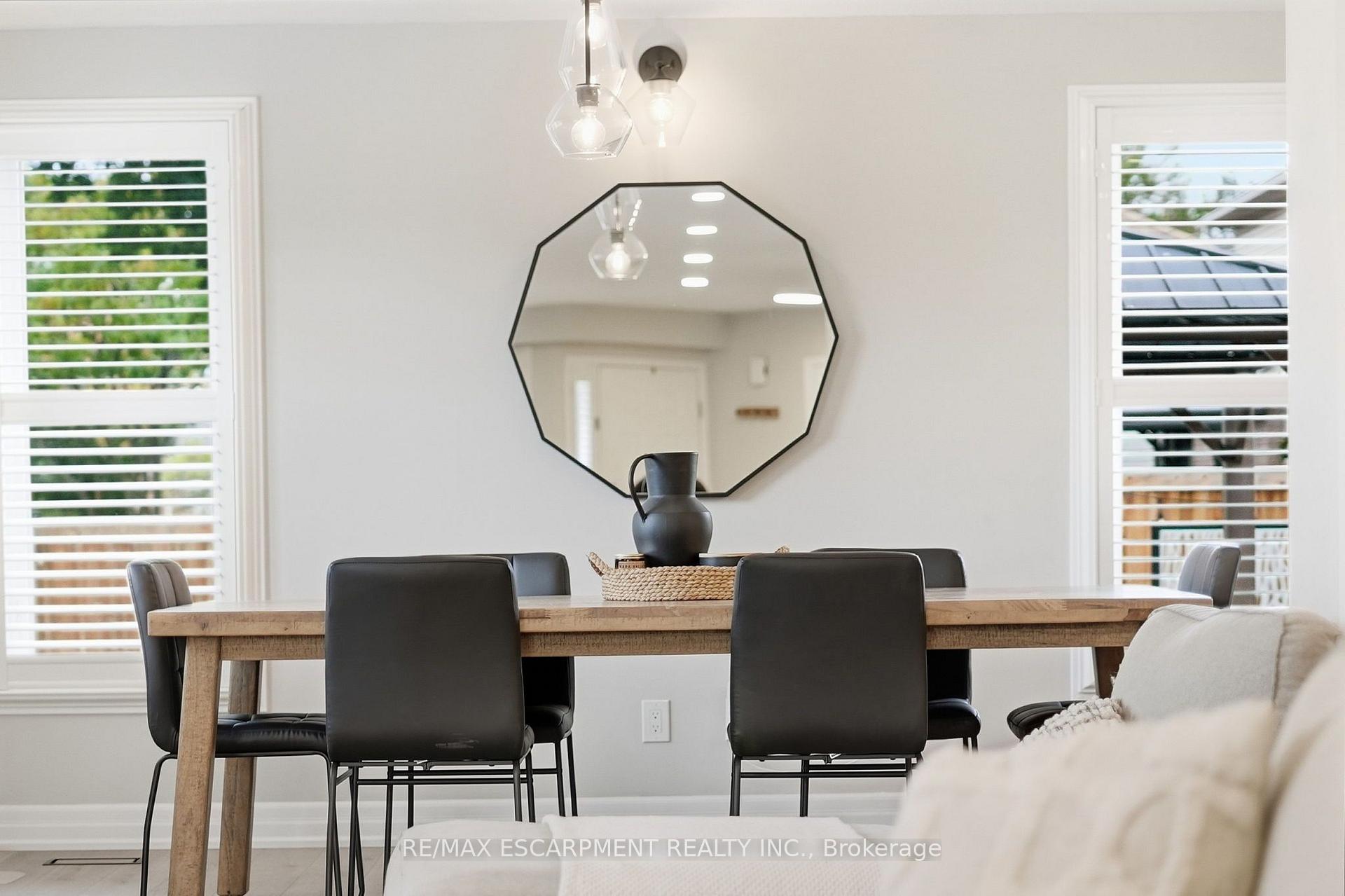 Dining room with a wood table, dark chairs, and a large octagonal mirror.