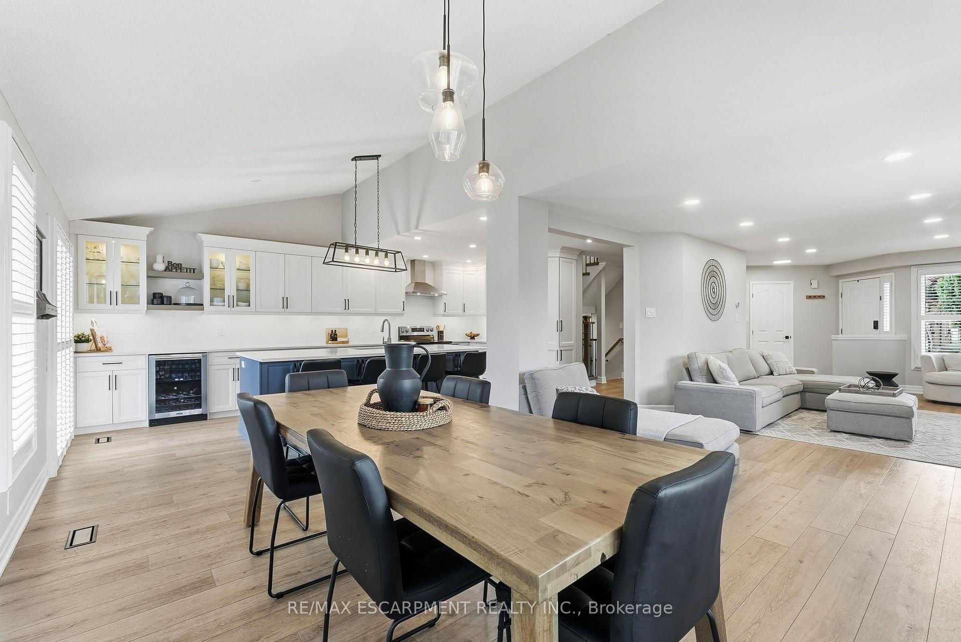 Open-concept kitchen, dining, and living area with a blue island and large wood dining table.