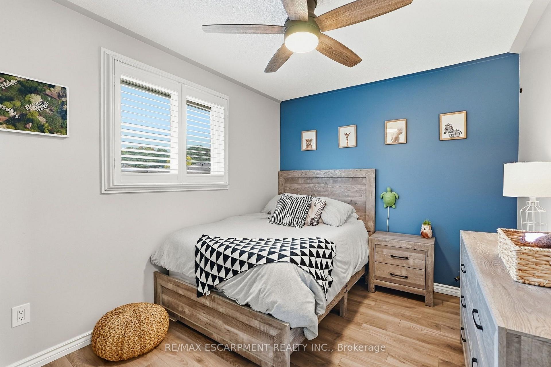 Furnished bedroom with a blue animal-print accent wall, wooden bed, and white plantation shutters.