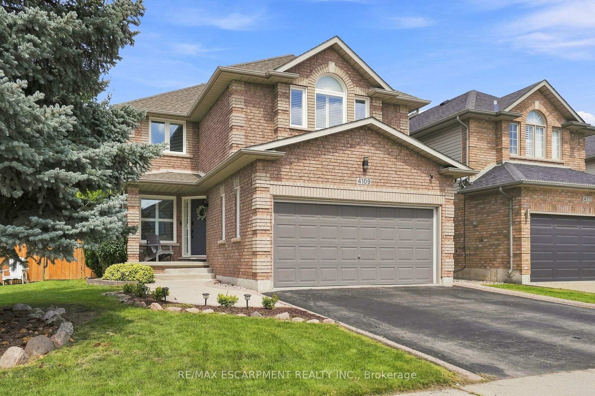 Two-story brick house with a double garage, covered entry, and landscaped front lawn.