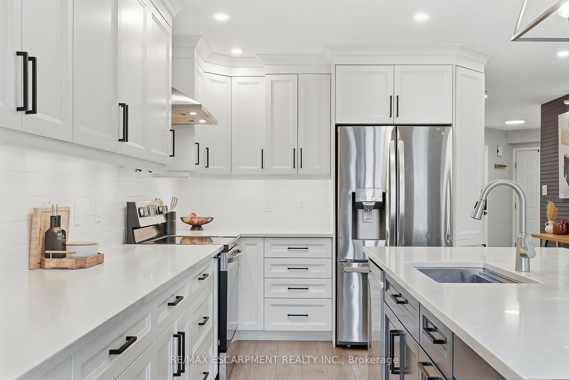 Bright white kitchen with shaker cabinets, stainless steel appliances, and a large island sink.