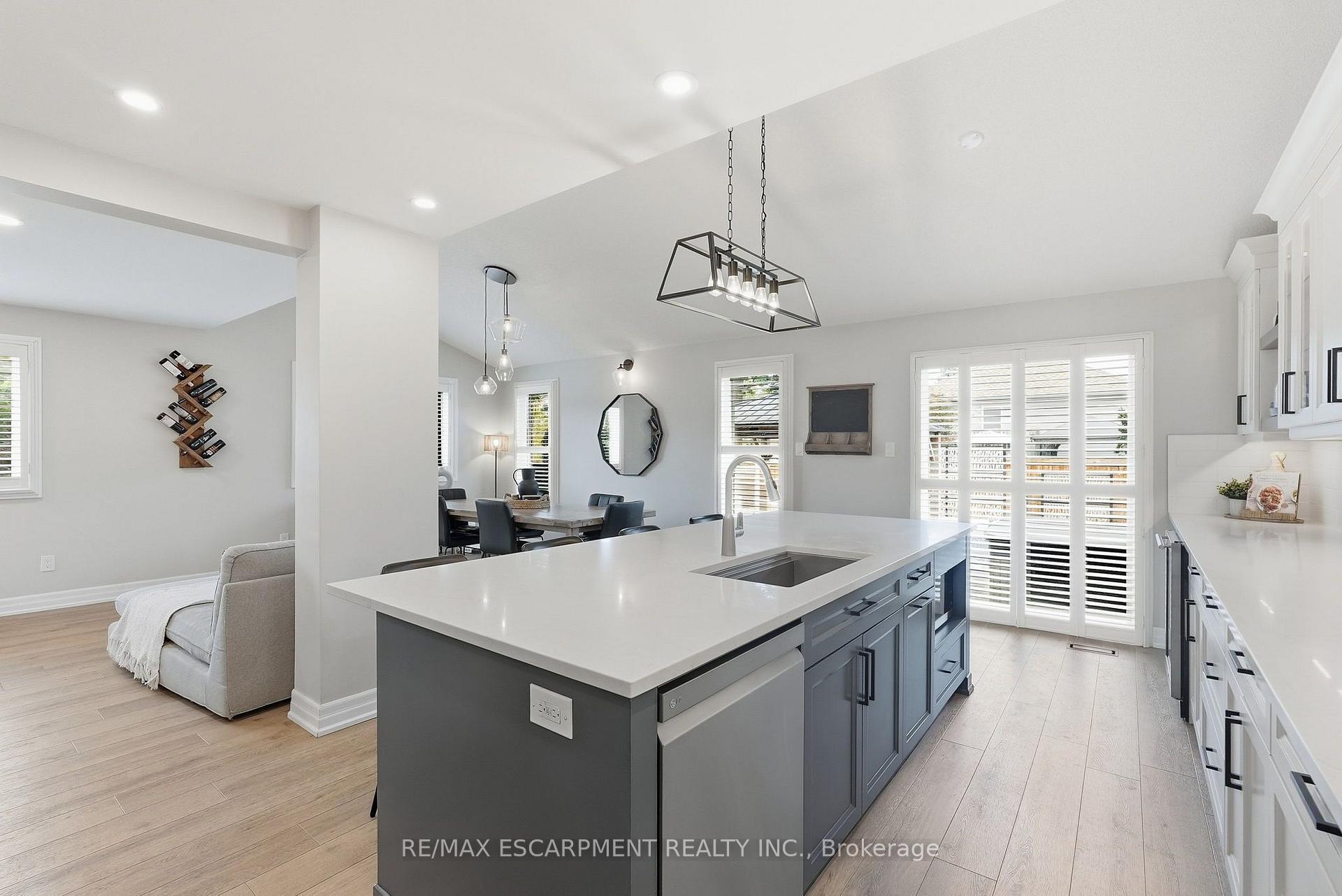 Open-concept kitchen with a large gray island and dining area beside shuttered patio doors.
