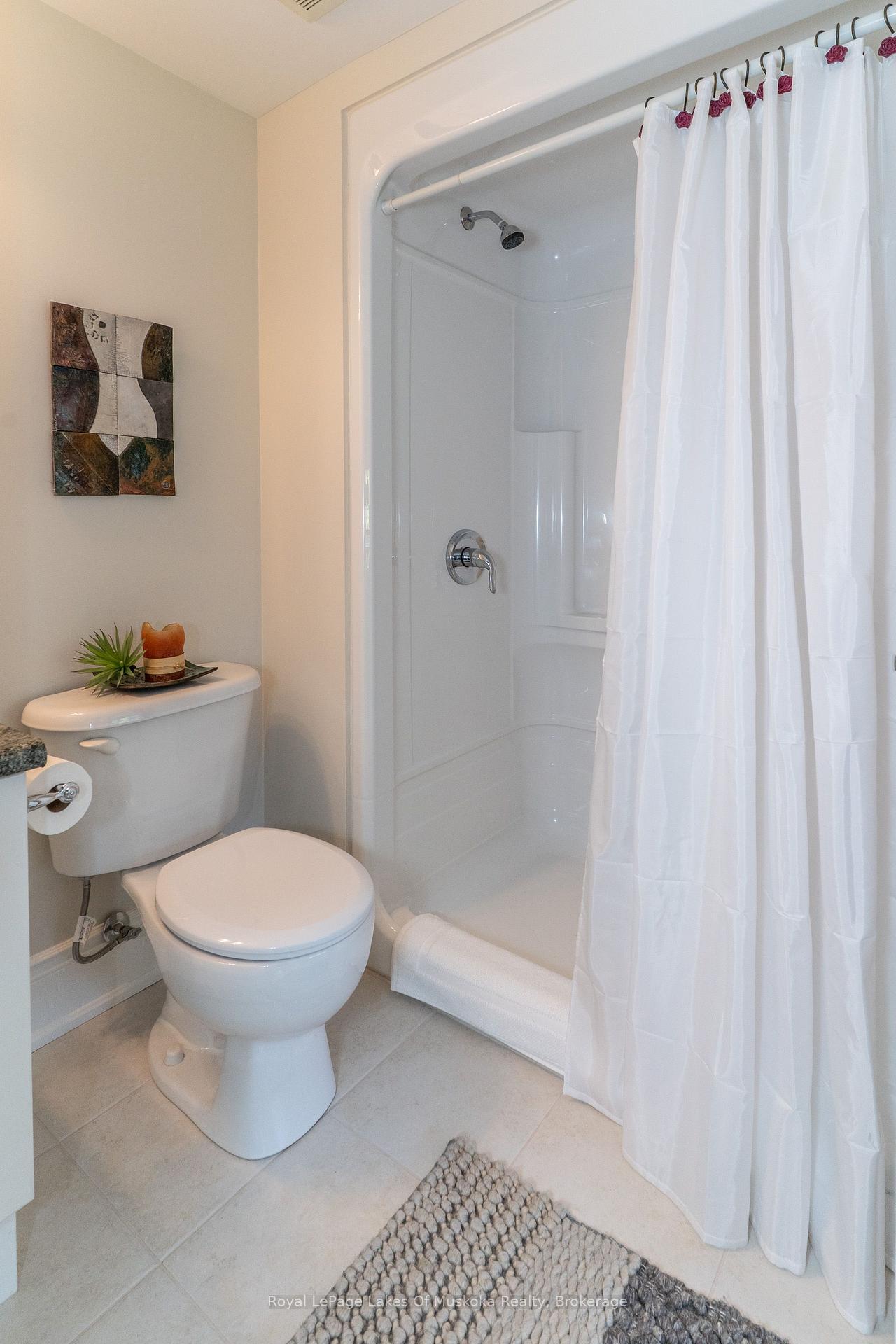 Bathroom with a white toilet beside a shower stall and curtain.