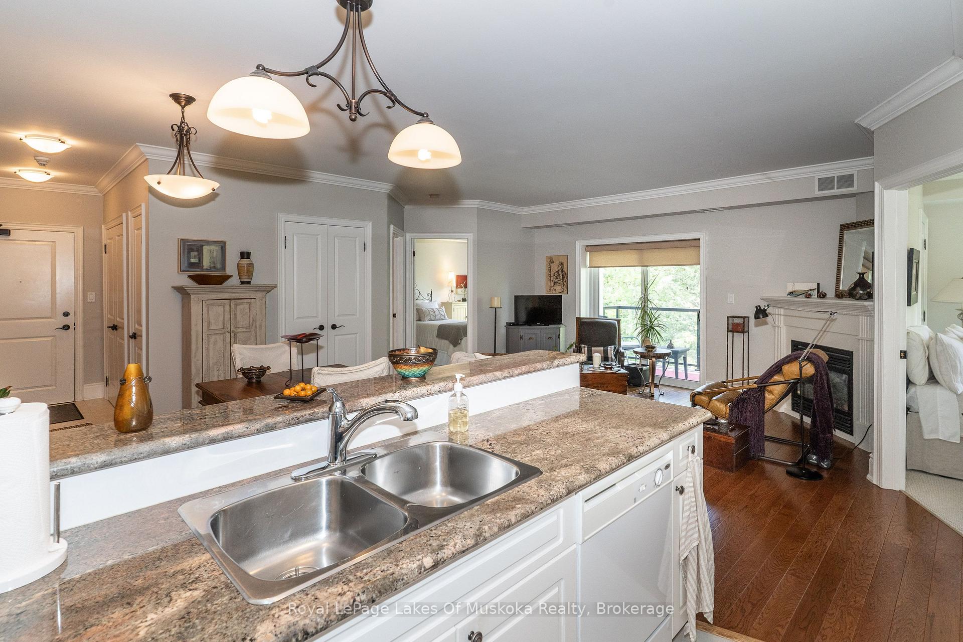 Open-plan condo kitchen and living room with granite breakfast bar, fireplace, and balcony doors.