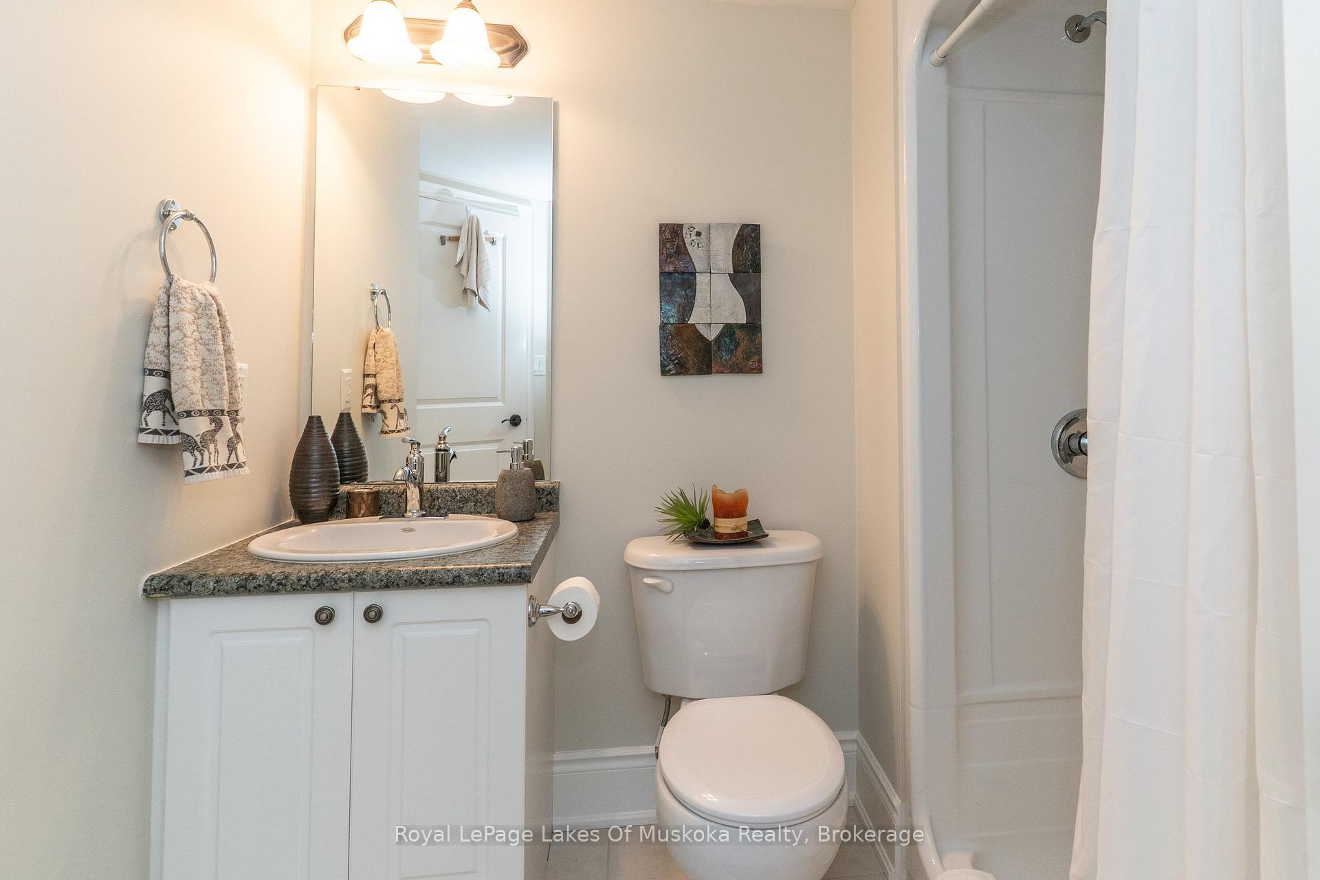 Bathroom with granite-topped vanity, oval sink, toilet, and white shower curtain.