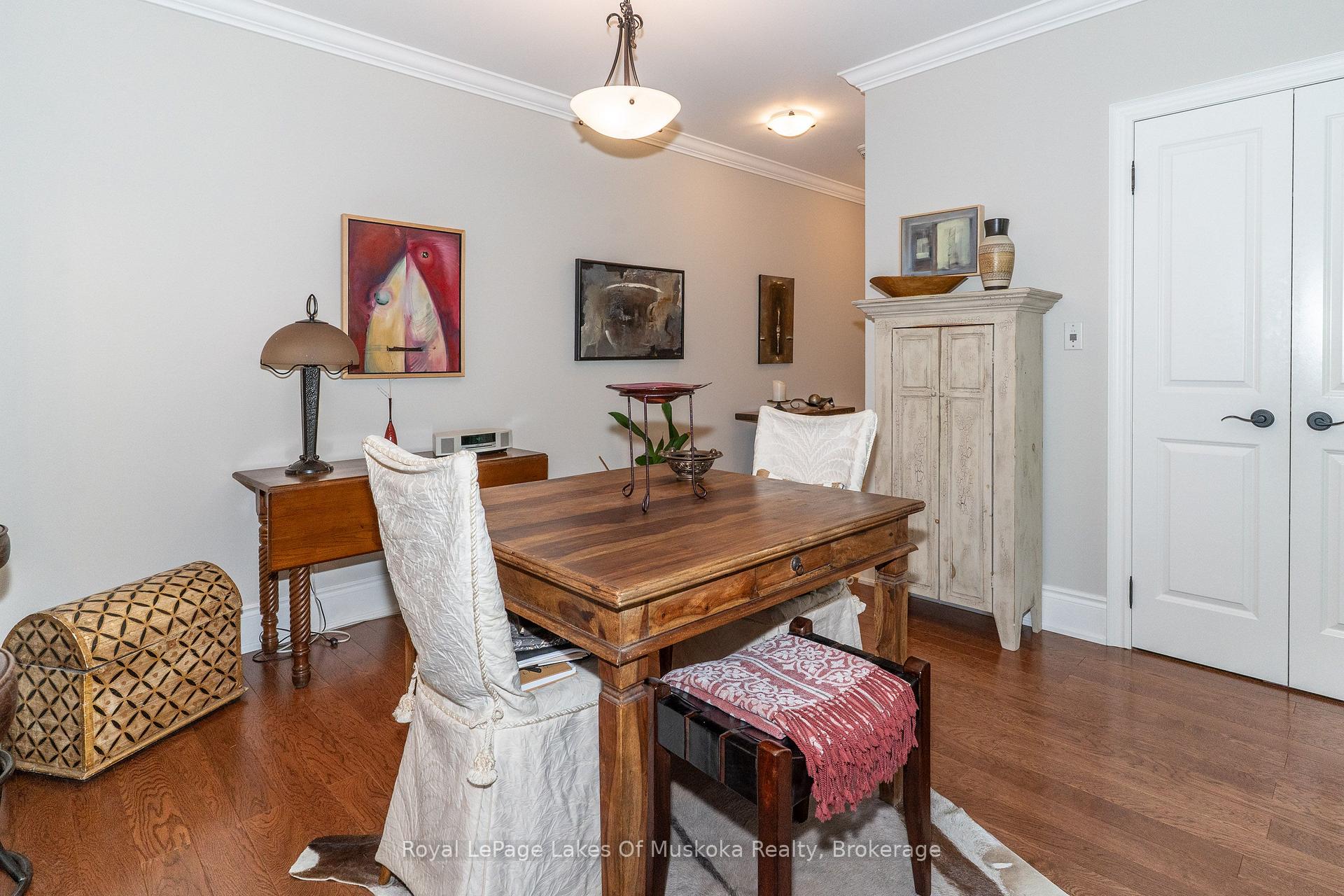 Dining room with a large wooden table, white chairs, and a distressed cream cabinet.