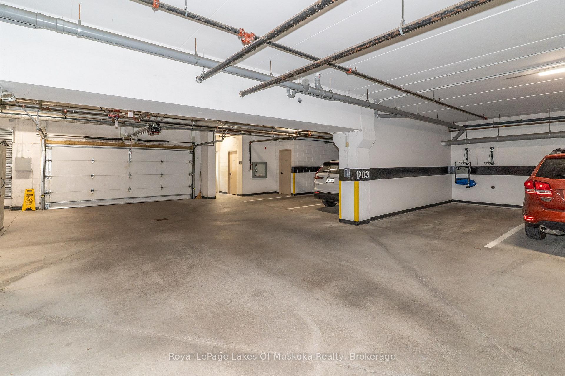 Indoor parking garage with exposed pipes, a concrete floor, and a parking divider marked P03.