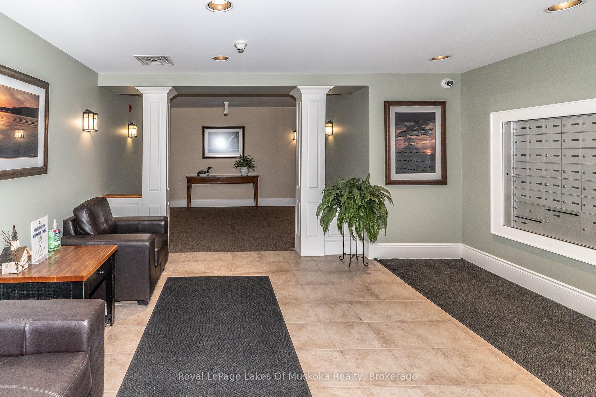 Condominium lobby with a wall of mailboxes, leather seating, and a potted fern.