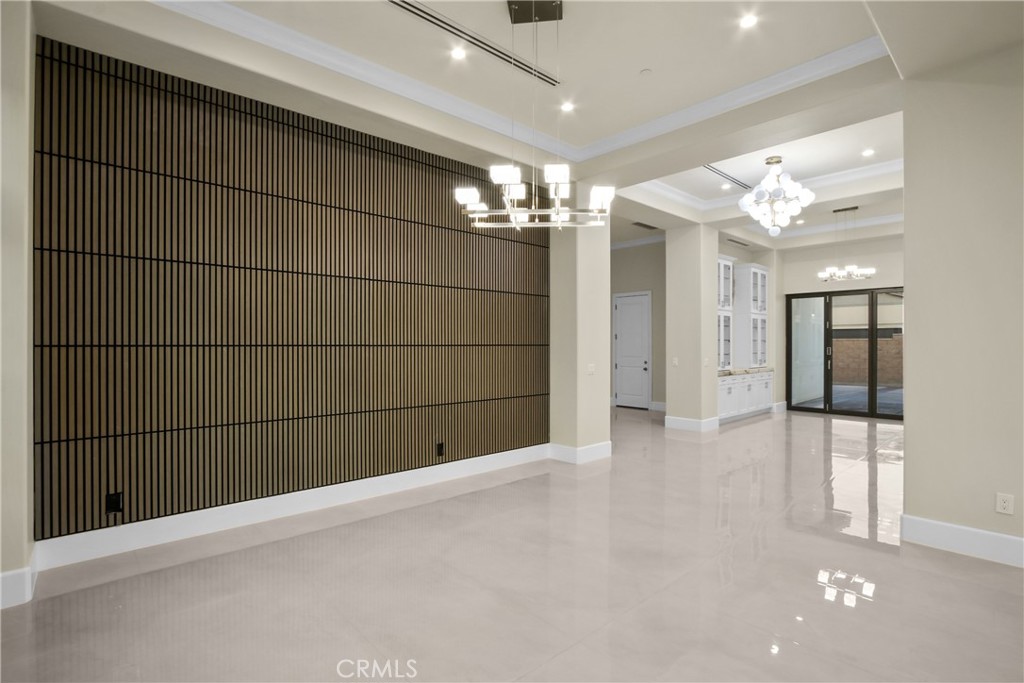 Open dining area with a dark slatted accent wall, chandeliers, and glossy tile flooring.