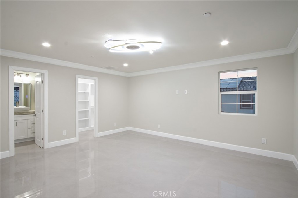 Empty bedroom with glossy tile floors, a window, and an adjoining bathroom.