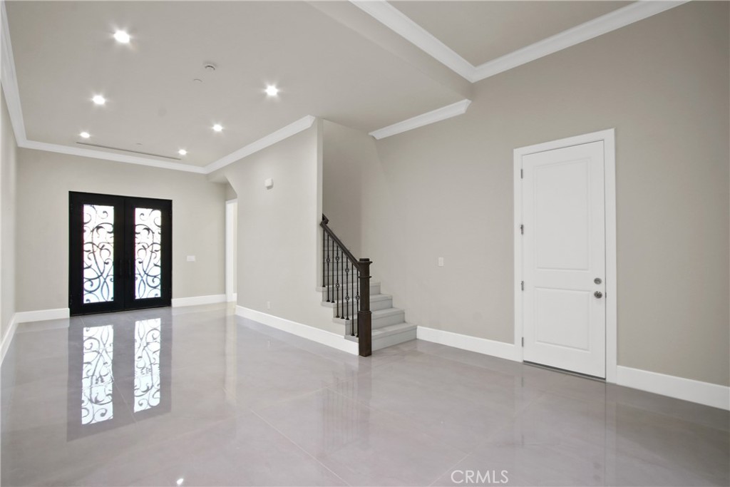Entry hall with glossy tile floors, ornate black double doors, and a short staircase.