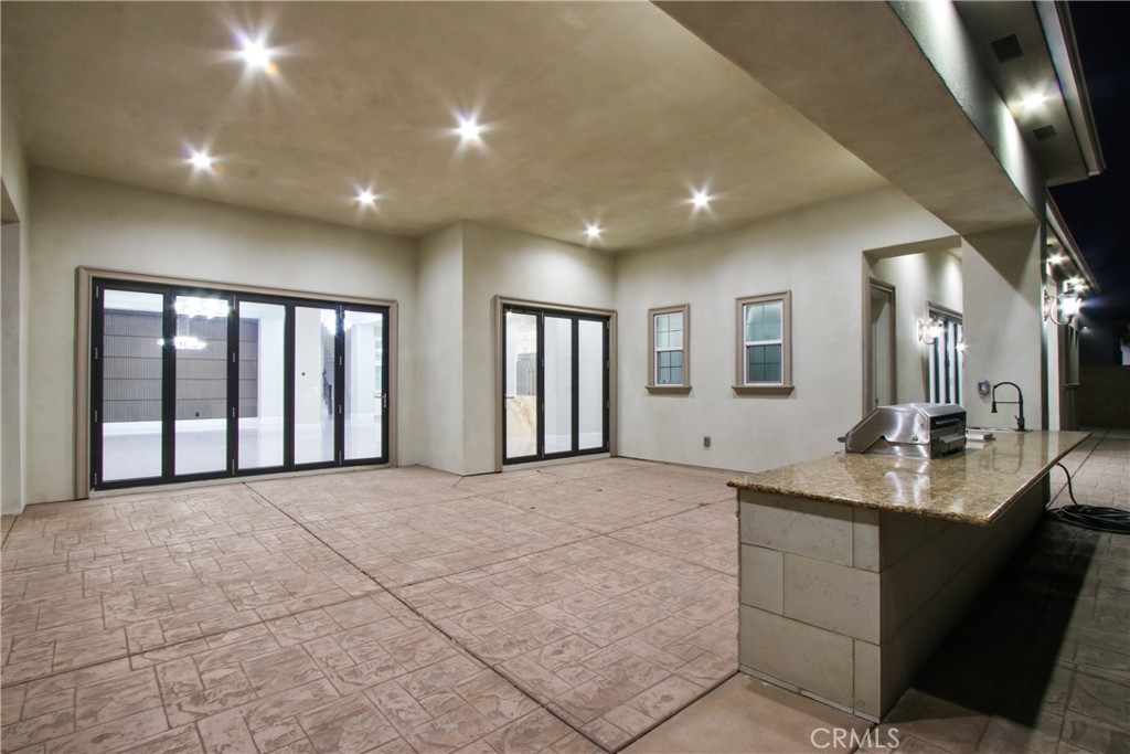 Covered patio with patterned tile, sliding glass doors, and a built-in outdoor grill and sink.