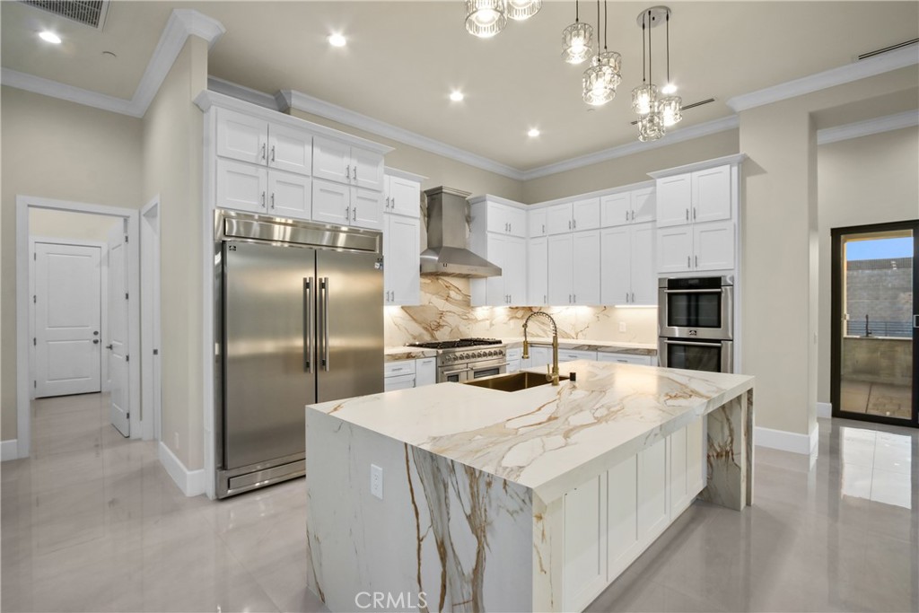 Modern kitchen with a veined marble waterfall island, white cabinets, and stainless steel appliances.