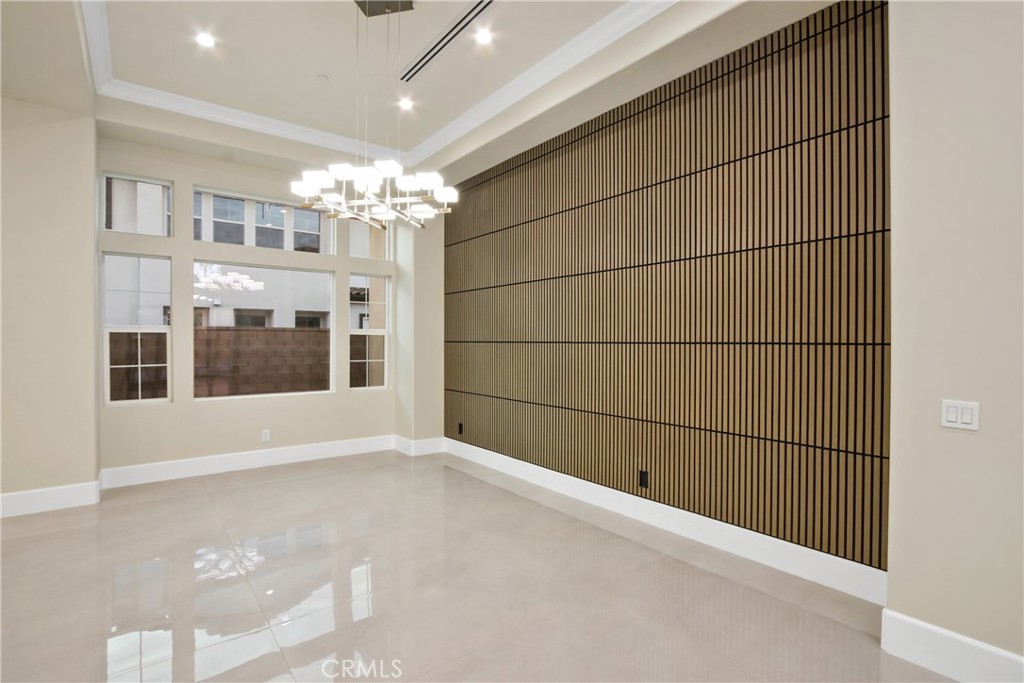 Vacant dining room with a wood-slat accent wall, chandelier, and large windows.