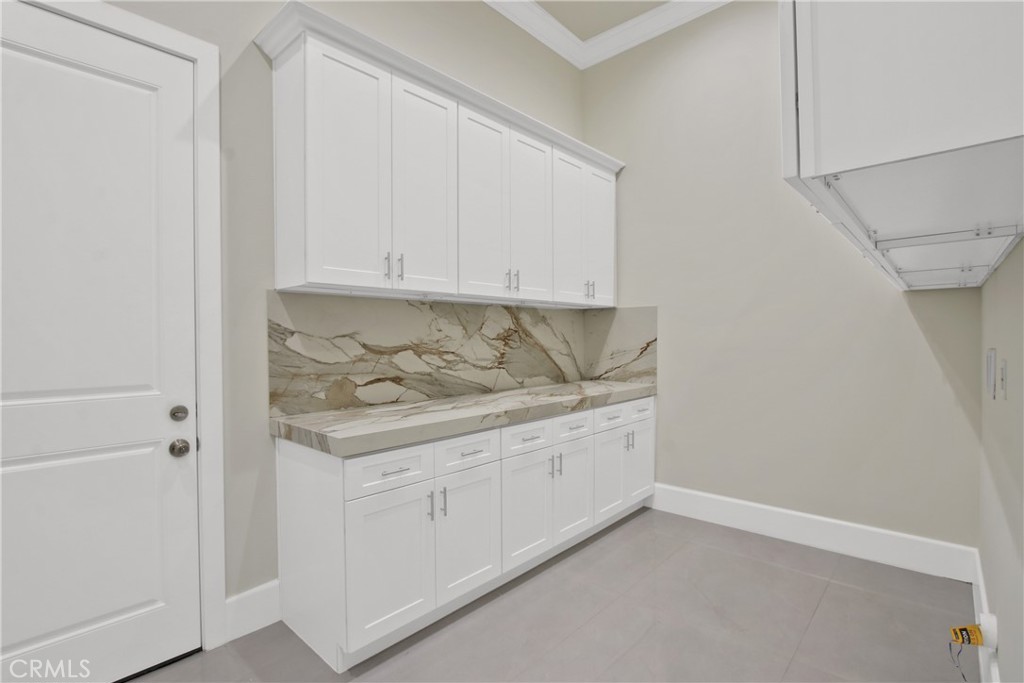 Utility room with white built-in cabinets and a dramatic veined stone backsplash and countertop.